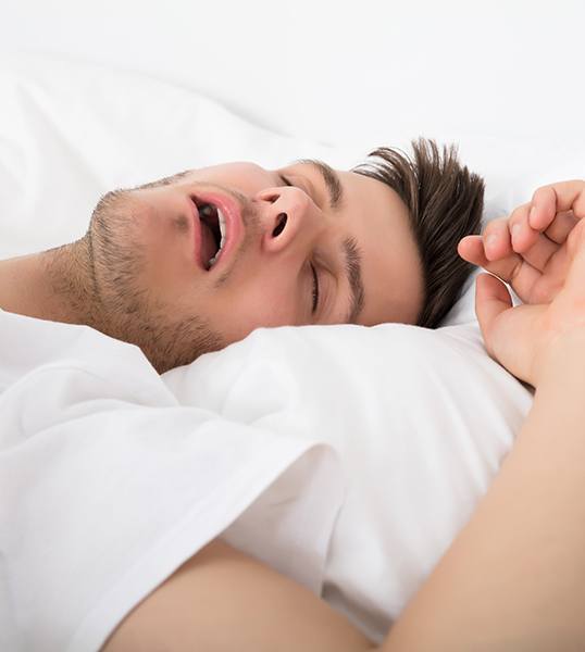 Man snoring in white bed sheets