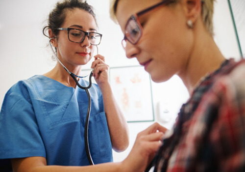 a doctor using a stethoscope to check a patient’s heart