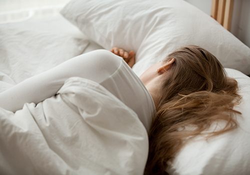 Woman sleeping in white bed linens