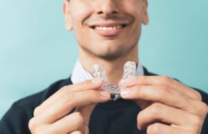 Smiling man holding oral appliance for sleep apnea